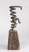 A primitive 19th Century iron and oak spiral candlestick, the spiral body with internal candle