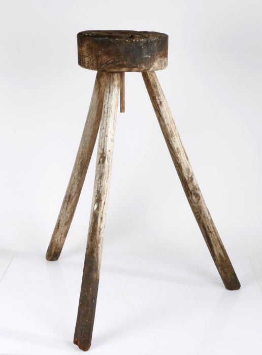 A 19th century wooden chopping block, cylindrical top raised on three faceted supports, 76cm high.