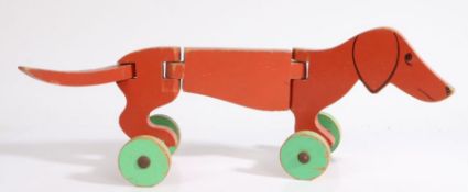 An early 20th Century Folk Art articulated wooden pull-along toy dog, painted in red with green