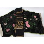 Near pair of silk work embroideries, each of pink flowers and green stems on a black ground,
