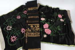 Near pair of silk work embroideries, each of pink flowers and green stems on a black ground,