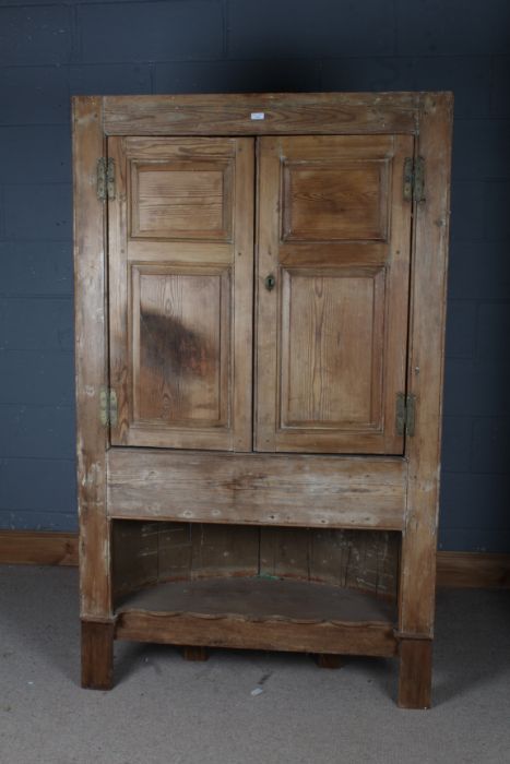 A large pine corner cupboard, with two doors opening to reveal two shelves above a open recess