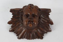 A 17th century style wall bracket, decorated with a cherubs head, 32cm wide 19cm high