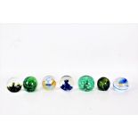 Seven glass paperweights to include a Victorian end of day green glass paperweight two Cathness