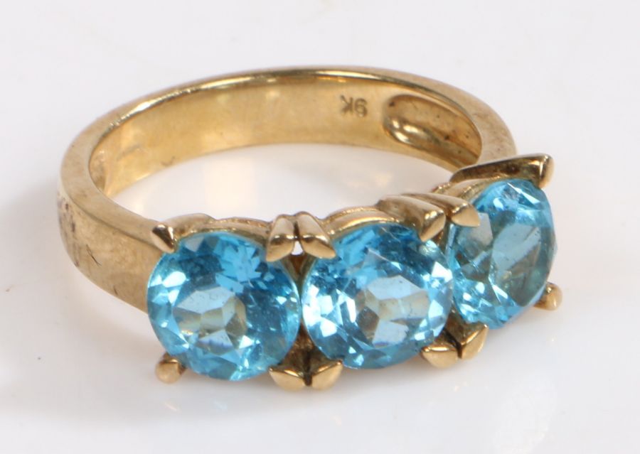 A 9 carat gold ring, the head set with three claw mounted brilliant cut vibrant blue stones, ring
