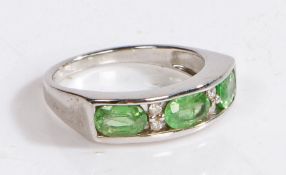 A 9 carat white gold, diamond and tsavorite ring, with three oval tsavorite stones intersected by