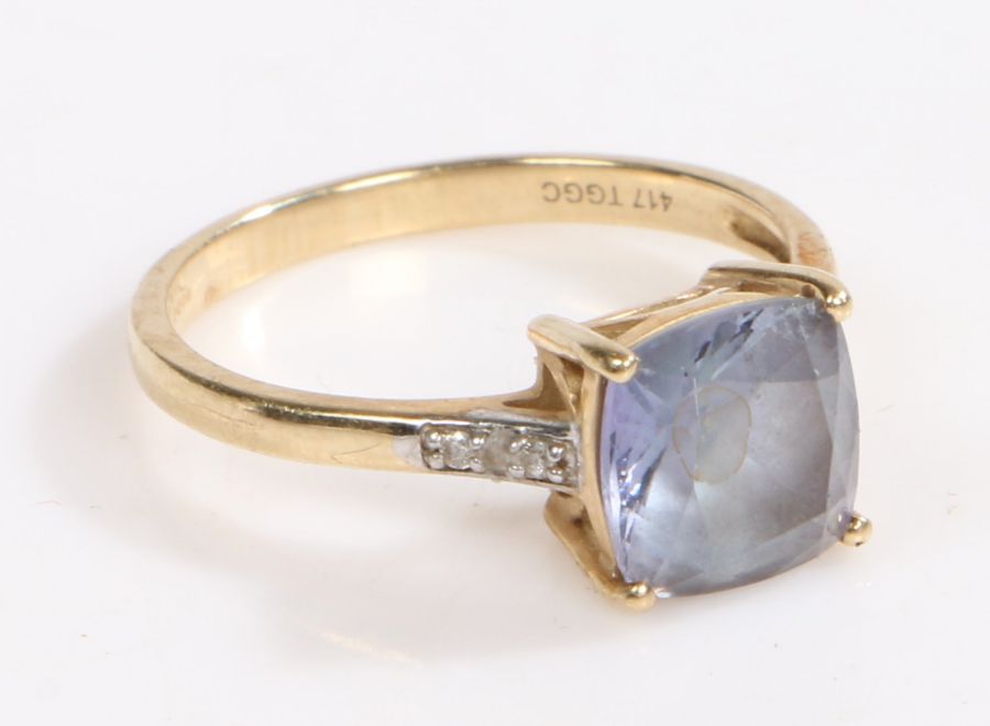 A 10 carat gold ring, the head set with a claw set asscher cut blue stone with three diamonds set to