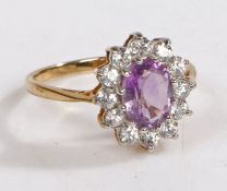 A 9 carat gold, amethyst and paste ring, the head set with a central oval amethyst surrounded by