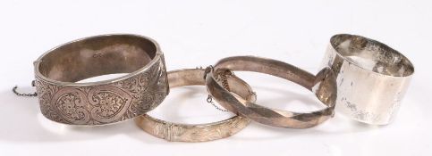 Three silver bangles together with a silver napkin ring, some with floral designs, gross weight 4.