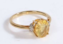 A 9 carat gold and diamond ring, the head set with a oval yellow stone with diamonds to the