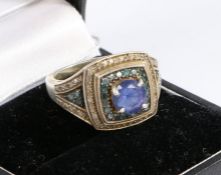 A silver, blue and white diamond ring, the head set with a central blue stone surrounded by rows
