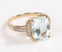 A 9 carat gold, diamond and aquamarine ring, the head set with claw mounted aquamarine with a row of