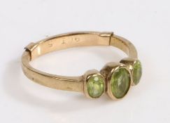 A 9 carat gold and peridot ring, the head set with three oval peridots, ring size P weight 2.5 grams