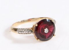 A 10 carat gold, diamond and garnet ring, set with a central brilliant cut diamond surrounded by