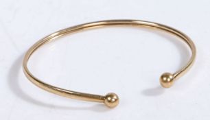 A 9 carat gold bangle with orb finials, hallmarked for Birmingham, weight 2.6 grams