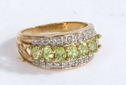 A 9 carat gold, diamond and peridot ring, the head set with a row of claw mounted oval peridots