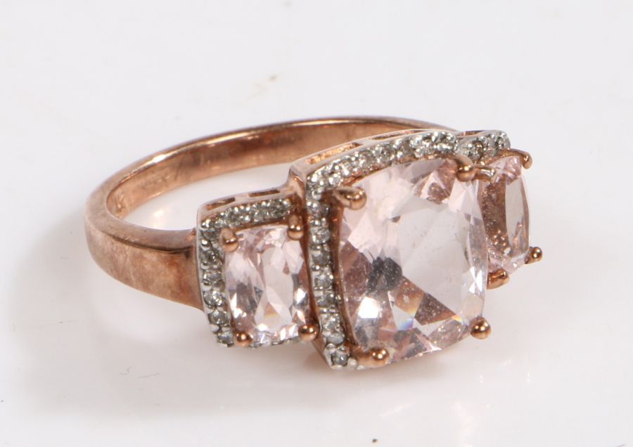 A 9 carat rose gold ring, the head set with three claw set glass stones surrounded by diamonds, ring