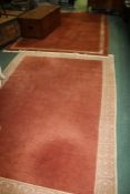 Three oriental wool rugs, all with a brick red ground, the largest 290cm by 190xm wide