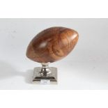 Ornamental wooden rugby ball, raised on square chromed base, 21cm high