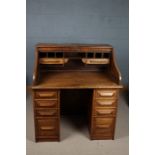 A 20th century Cutler golden oak tambour roll top pedestal desk with eight drawers to the