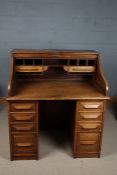 A 20th century Cutler golden oak tambour roll top pedestal desk with eight drawers to the