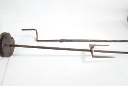Iron roasting spit rods, with wooden pulley and adjustable fork to one section, the opposing side