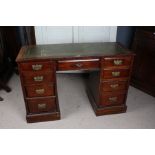 A 20th century mahogany leather topped desk, with a green leather and gilt tooled top above nine