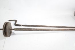 Iron roasting spit rods, with wooden pulley to one section, the opposing side with handle