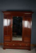 20th century mahogany triple wardrobe, with a carved cornice above a single beveled glass door