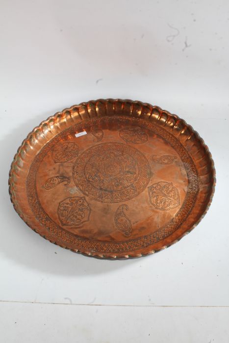 Eastern copper tray, with pinched border and centred with a scroll motif, 54cm diameter