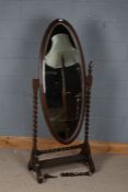 A 20th century oak cheval mirror, the oval mirror with barley twist supports raised on scroll