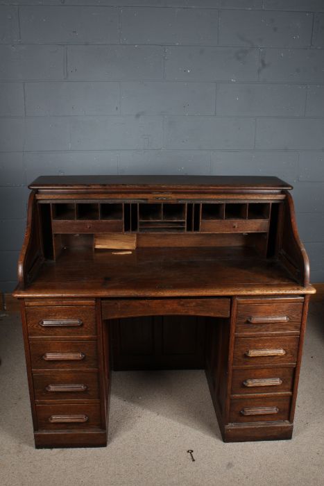 Early 20th century oak writing desk, the tambour top enclosing a pigeon hole interior, fitted four