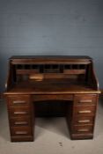 Early 20th century oak writing desk, the tambour top enclosing a pigeon hole interior, fitted four