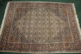 Large middle eastern rug with a cream, blue and orange ground with many floral guls of various forms