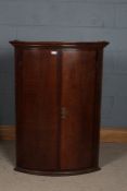 A George III oak bowfront corner cupboard with a pair of doors with cross banded inlaid, opening