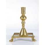 A brass tray-base candlestick, Spanish, circa 1700 Having a cylindrical socket with mid-fillet,