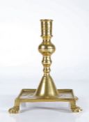 A brass tray-base candlestick, Spanish, circa 1700 Having a cylindrical socket with mid-fillet,