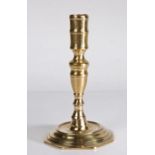 A late 17th century brass candlestick Having a tall socket, of waisted form with central fillet,