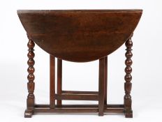 A Charles II walnut gateleg occasional table, circa 1680 Having an oval drop-leaf top, on ball-
