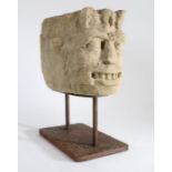 A carved limestone corbel head, probably 12th century Designed as a grotesque, with leafy 'crown',