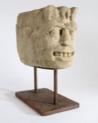 A carved limestone corbel head, probably 12th century Designed as a grotesque, with leafy 'crown',