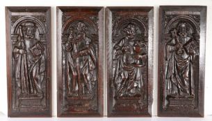 Four 16th century carved oak panels of Saints, circa 1530 Each standing beneath an arch, on a