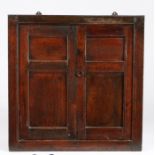 A late 17th century oak mural cupboard, circa 1700 With two double-panelled doors, enclosing two