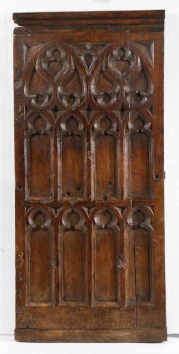 A 15th century oak pew end, circa 1450 Carved with oculi, mouchettes and tracery lights, rounded