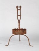 A wrought iron torchiere  Having a slender open 'basket', the side straps each with disc finial,