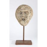 A carved stone Green Man head, possibly 12th century With downward looking eyes, open mouth possibly