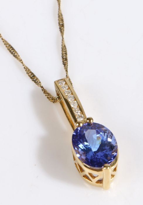 A 9 carat gold pendant and chain link necklace, the pendant set with a oval tanzanite stone with
