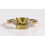 A 9 carat gold diamond and yellow sapphire ring, the head set with a claw mounted cushion cut yellow