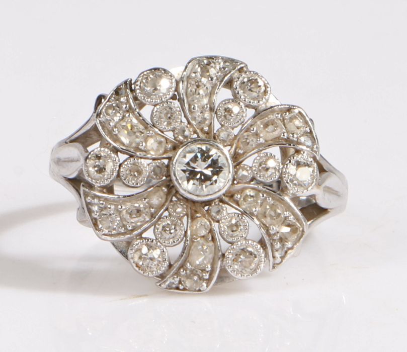 A diamond ring, set in white metal the head in the form of a flower, set with a central brilliant