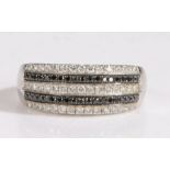 A 14 carat gold white and black diamond ring, the head set with three rows of white round cut
